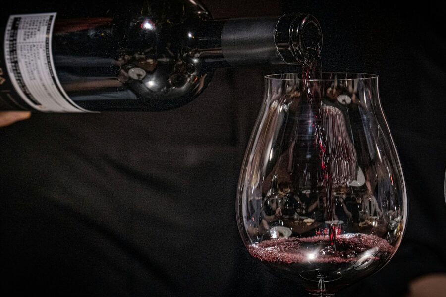 Vinho tinto sendo servido em taça para ilustrar a comparação entre Cabernet Sauvignon e Merlot